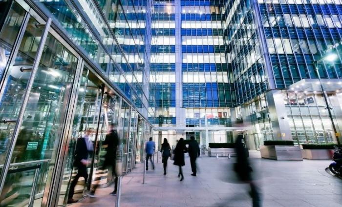 Blurred people as they rush through a busy city with skyscrapers behind them