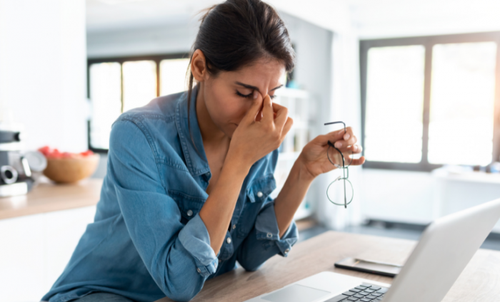 Woman holding her head in her hands as she suffers Zoom fatigue