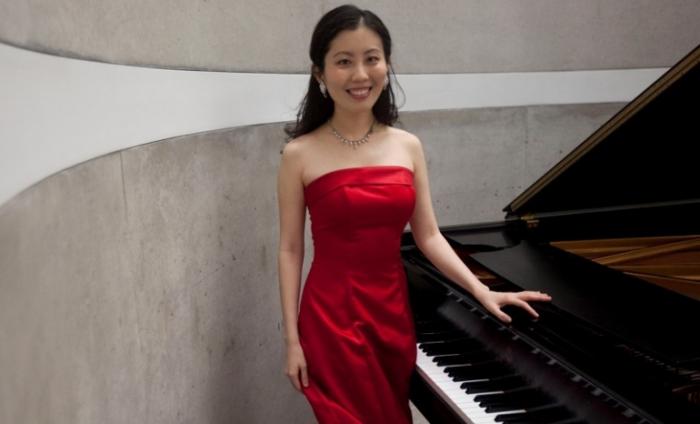 Photo of Chia-Jung Tsay standing next to a grand piano smiling