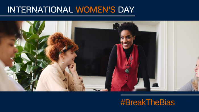 Women in a meeting smiling and working. Image has the words "International Women's day" and "#BreakTheBias" overlaid.