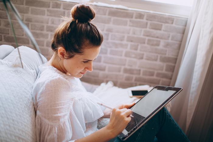 Brunette woman in a white top working on a tablet