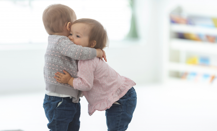 One toddler hugging another